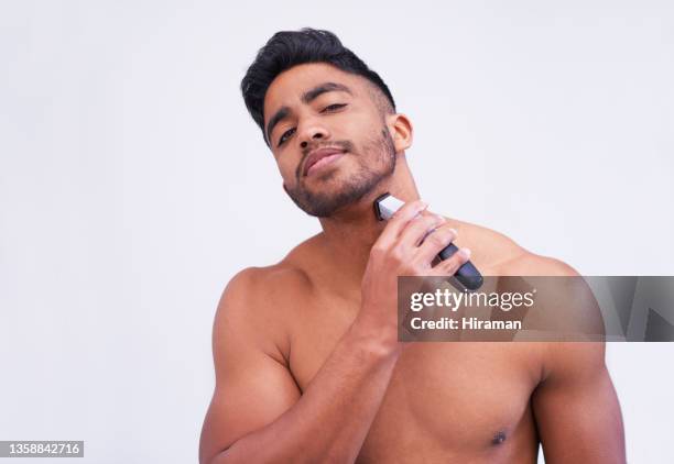 portrait of a handsome young man using an electric shaver against a white background - male hair removal stockfoto's en -beelden