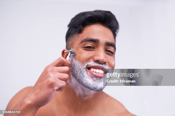 portrait of a handsome young man shaving his facial hair against a white background - man shaving foam stock pictures, royalty-free photos & images
