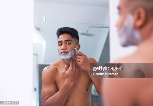 aufnahme eines gutaussehenden jungen mannes, der sich im badezimmer zu hause die gesichtsbehaarung rasiert - man shaving face stock-fotos und bilder