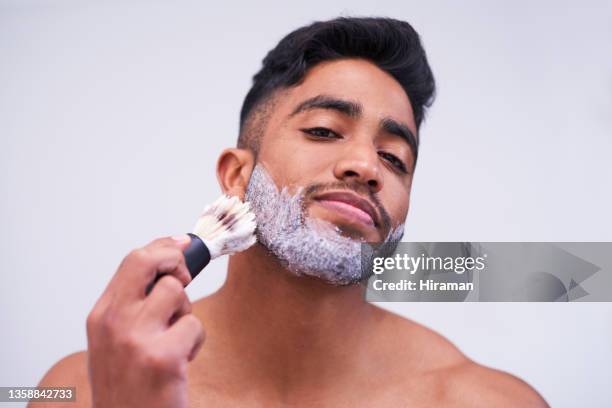 portrait of a handsome young an applying shaving cream to his face with a brush against a white background - man shaving foam stock pictures, royalty-free photos & images