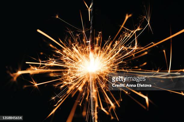 burning sparklers with many beautiful sparks on black background. concept of new year or birthday celebration - funken stock-fotos und bilder