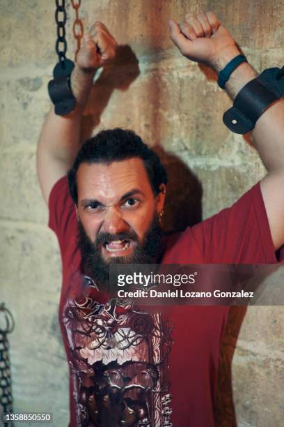 hispanic man in handcuffs pretending to be prisoner in medieval castle - medieval torture stock pictures, royalty-free photos & images