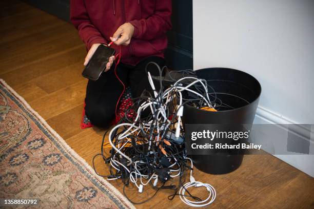 young man trying to find a phone charger from a jumble of cables - untangle stockfoto's en -beelden