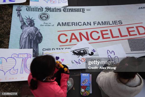 Children draw on top of a 'cancelled check' prop during a rally in front of the U.S. Capitol December 13, 2021 in Washington, DC. ParentsTogether...