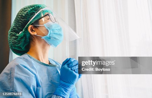 Healthcare worker praying for god blessing while wearing safety equipment for working in hospital during coivd-19 pandemic. Healthcare worker praying for god blessing while wearing safety equipment for working in hospital during coivd-19 pandemic.