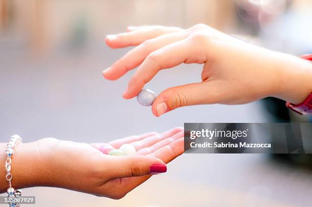 two hands sharing candies - offering candy fotografías e imágenes de stock