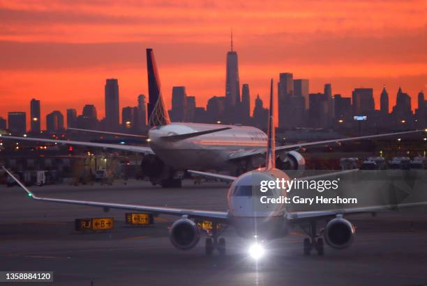 United Airlines airplane proceeds to a gate at Newark Liberty International Airport as the sun rises behind the skyline of lower Manhattan and One...