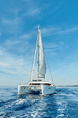 Luxury catamaran sailing under white sails on the blue azure sea