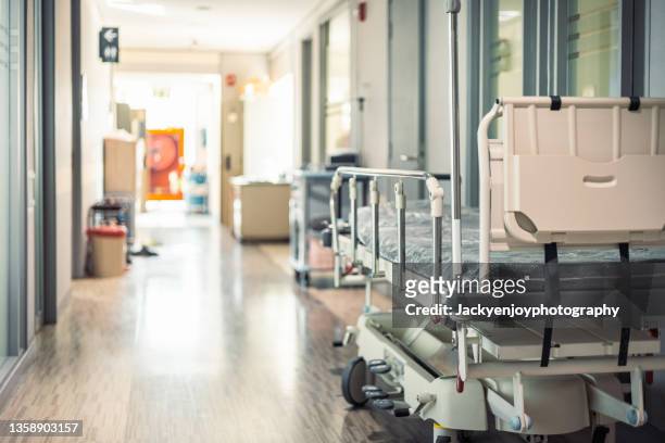 empty hospital beds in hospital corridor - krankenhaus stock-fotos und bilder