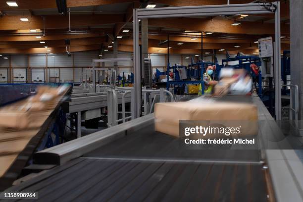 eine frau arbeitet vor einem förderband in einem postpaketsortierzentrum - boxes conveyor belt stock-fotos und bilder