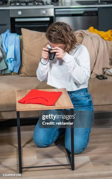 view of a young female who is shooting a red t-shirt on a table. she is into online marketing. she is going to sell it. she is making money by selling her second-hand stuff. - secondhand försäljning bildbanksfoton och bilder