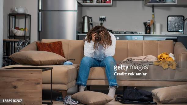 view of a young female who is addicted to cocaine. she is in a drug crisis. sitting on a sofa. she messed up everywhere and she doesn’t know what to do. she doesn’t have enough money to buy cocaine. she got involved in the drug environments in college. - symptom stockfoto's en -beelden