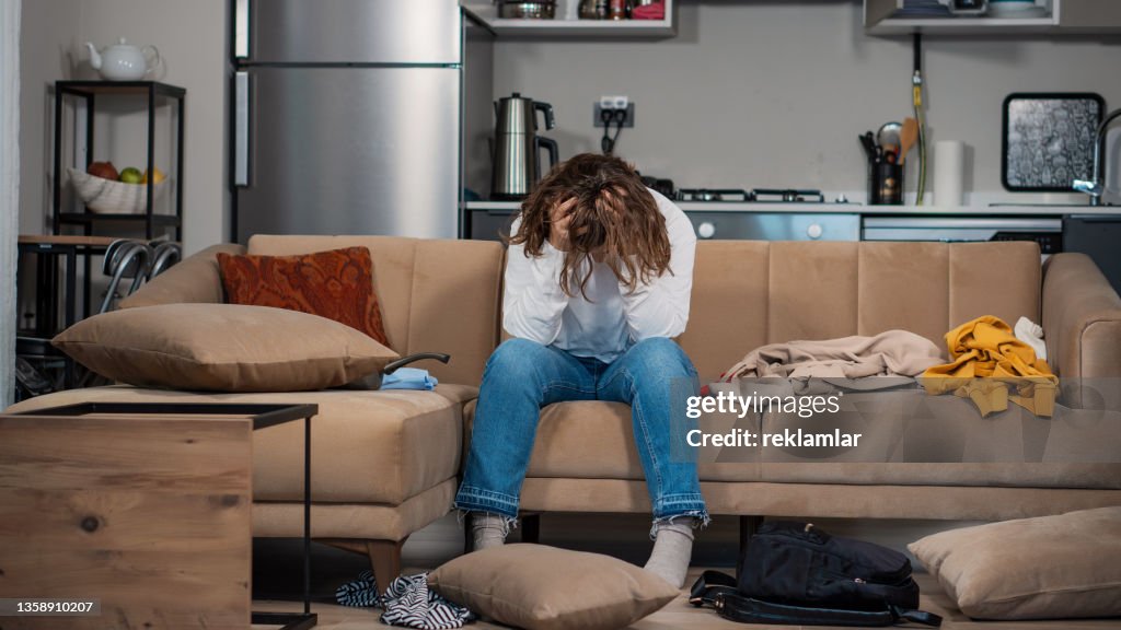View of a young female who is addicted to cocaine. She is in a drug crisis. Sitting on a sofa. She messed up everywhere and she doesn’t know what to do. She doesn’t have enough money to buy cocaine. She got involved in the drug environments in college.