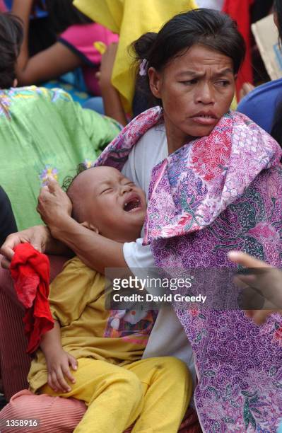 An unidentified mother holds her child as they wait with approximately 1,500 other Filipino deportees to disembark a navy ship August 29, 2002 in...
