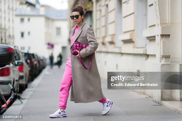 Katie Giorgadze @katie.one wears a black sunglasses, a neon pink recycled cotton sweater, matching neon pink recycled cotton sport pants / jogger...