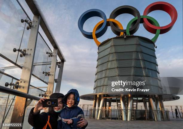 Visitors pose for photos near a column with the Olympic Rings as they visit the top level of the Olympic Tower in the Olympic Green near the National...