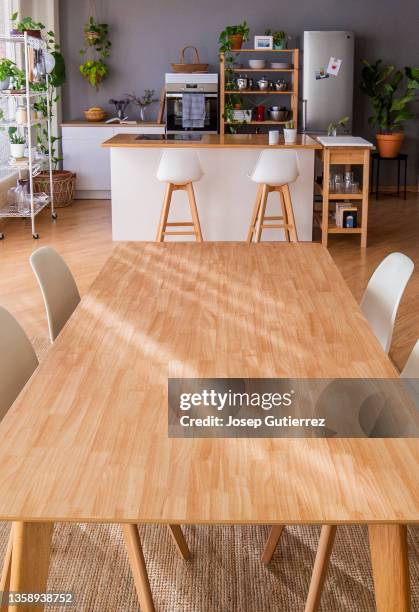 island kitchen and long table with chairs at a open space studio - long wooden table stock pictures, royalty-free photos & images