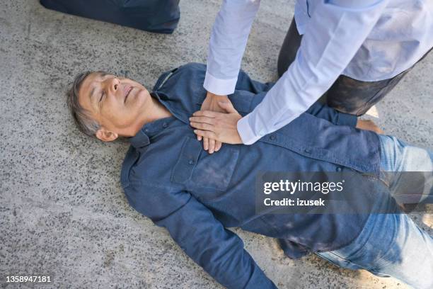 frau, die einem älteren mann erste hilfe leistet - wiederbelebung stock-fotos und bilder