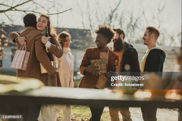 hosts and guests greeting in warm autumnal sunshine - fall party arrivals stockfoto's en -beelden