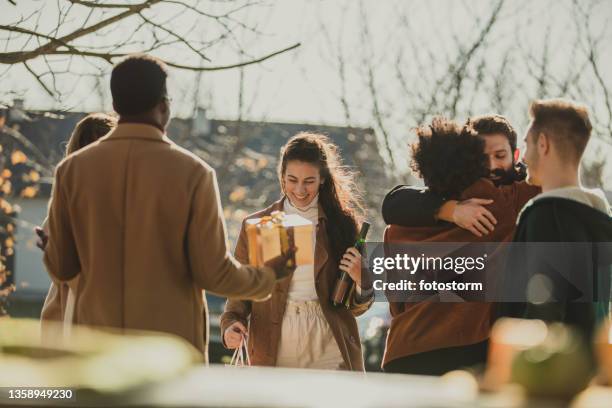 groupe d’amis embrassant et saluant leurs hôtes sous un chaud soleil d’automne - fall party arrivals photos et images de collection