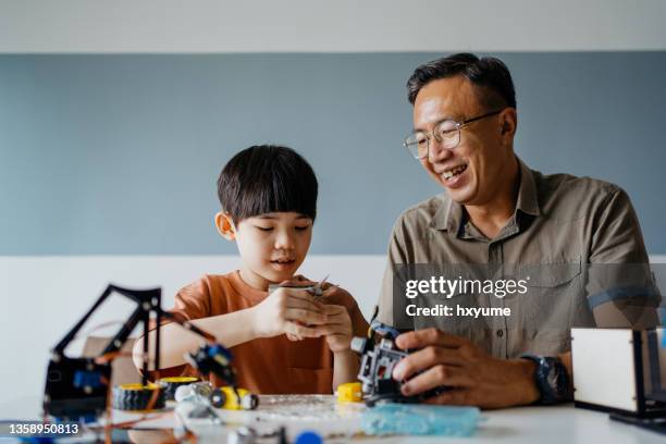 vater und sohn bauen roboterspielzeug zu hause - children learning creative stock-fotos und bilder