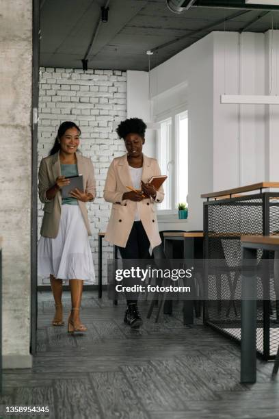 two businesswomen walking to the meeting, chatting casually - farewell colleague stock pictures, royalty-free photos & images