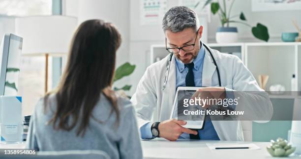 aufnahme eines reifen arztes, der mit seiner patientin sitzt und ihre röntgenaufnahmen auf einem digitalen tablet zeigt - lunge krank stock-fotos und bilder