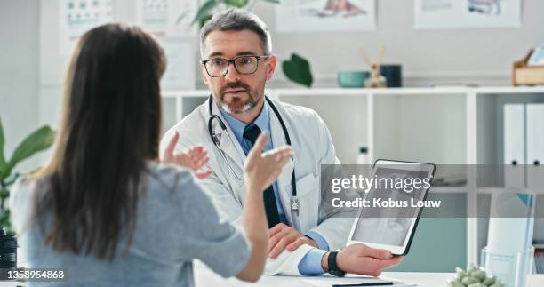 shot of a mature doctor sitting with his patient and discussing her x-rays while using a digital tablet - patient information stock pictures, royalty-free photos & images