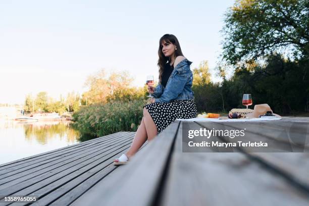 a beautiful girl is sitting on the dock near the water. - spotted lake stock pictures, royalty-free photos & images