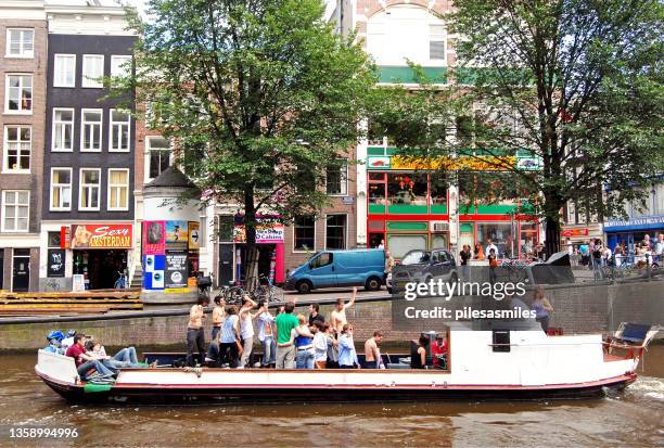 party barge and revelers, amsterdam, capital city, netherlands, - amsterdam mensen boot stockfoto's en -beelden