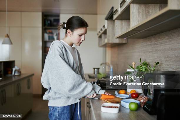 a 12-year-old schoolgirl prepares a lunch box for school from vegetables , fruits and nuts - old person kitchen food ストックフォトと画像
