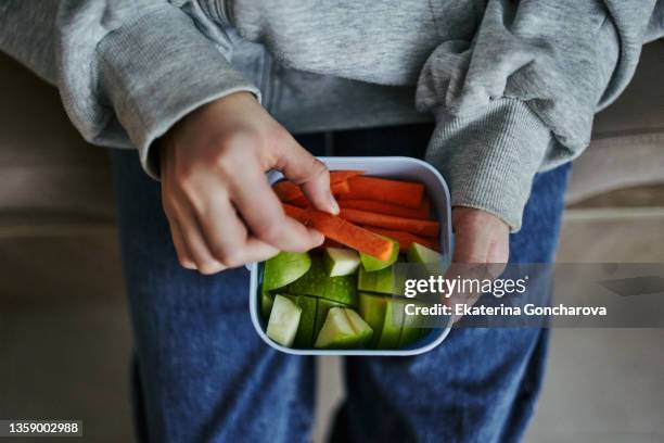 close-up of a lunch box in the hands of a child with healthy food, nuts, carrots and an apple. - kids eating healthy stock pictures, royalty-free photos & images