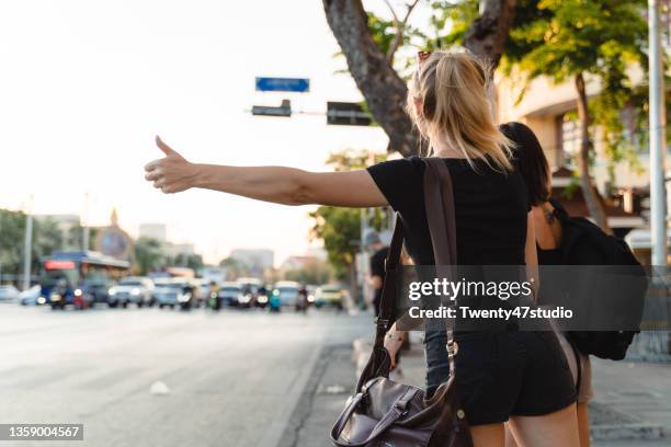 rear view of females hitchhiking public taxi at khao san road in bangkok thailand - hitchhike stock-fotos und bilder