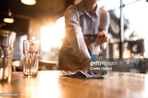 waitress cleaning tables with disinfectant in a cafe. - restaurant cleaning stock pictures, royalty-free photos & images