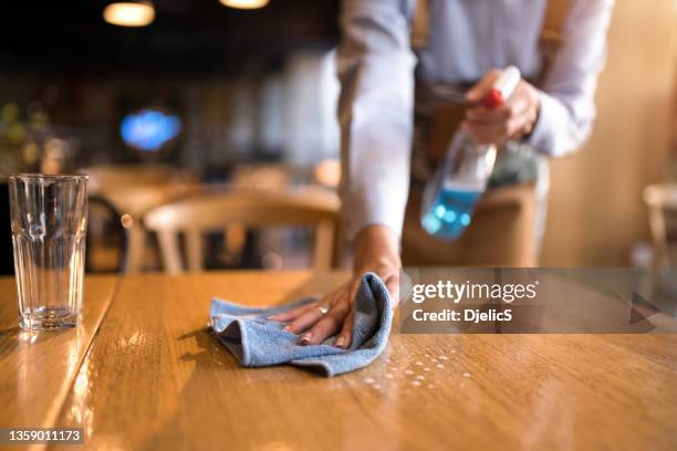 waitress cleaning tables with disinfectant in a cafe. - restaurant cleaning stock pictures, royalty-free photos & images