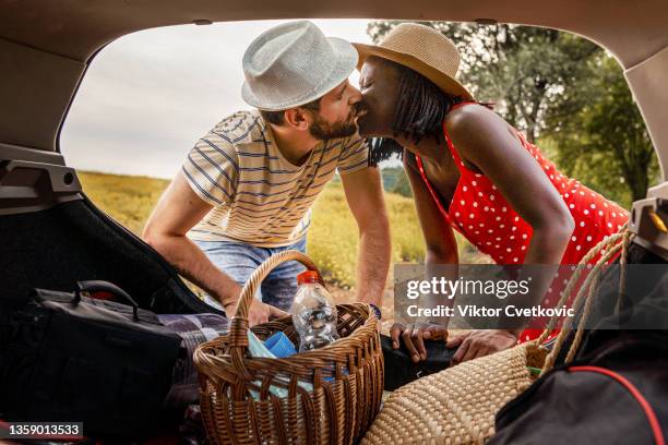 man and wife kissing while unpacking back of the car - black women kissing white men stock pictures, royalty-free photos & images