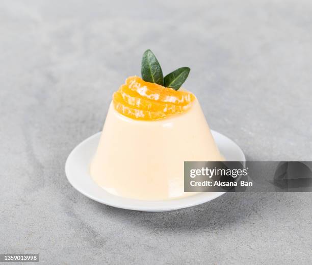 tangerine panna cotta on a plate on a light gray background - panna cotta photos et images de collection