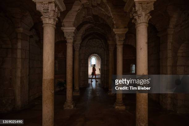 a woman walks under an archway in crypt of the abbaye saint philibert - krypta stock-fotos und bilder