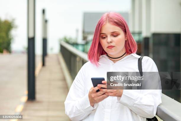 outdoors portrait of attractive 20 year old woman with pink hair - 20 year woman looking no smile casual setting stock pictures, royalty-free photos & images
