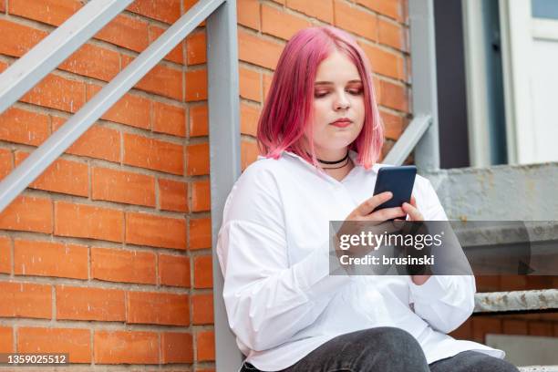 outdoors portrait of attractive 20 year old woman with pink hair - 20 year woman looking no smile casual setting stock pictures, royalty-free photos & images