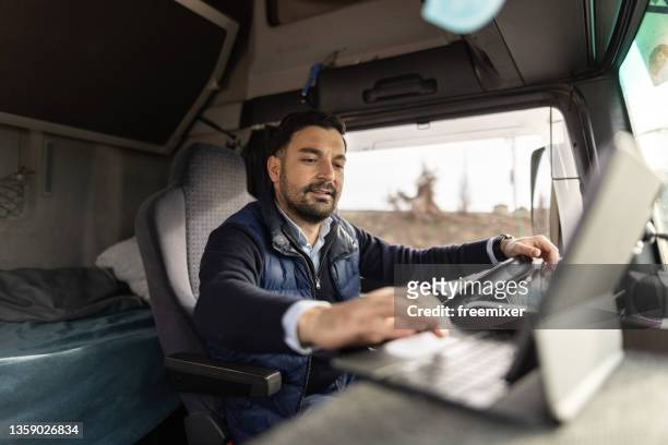 truck driver typing destination on tablet while sitting in cabin - chaufför bildbanksfoton och bilder