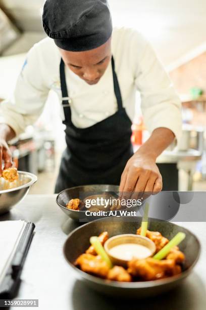 chef in restaurant kitchen preparing a meal - black cook stockfoto's en -beelden