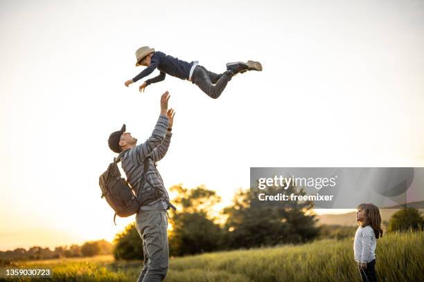 father spending time with his two kids in nature while throwing son into air - dad throwing kid in air stockfoto's en -beelden