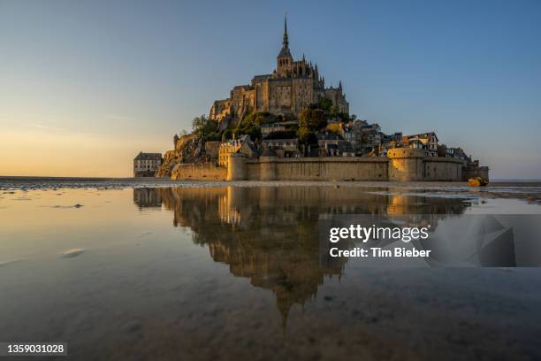 looking across the tidal water at the majestic abby of le mont-saint-michel - hogwarts stock pictures, royalty-free photos & images