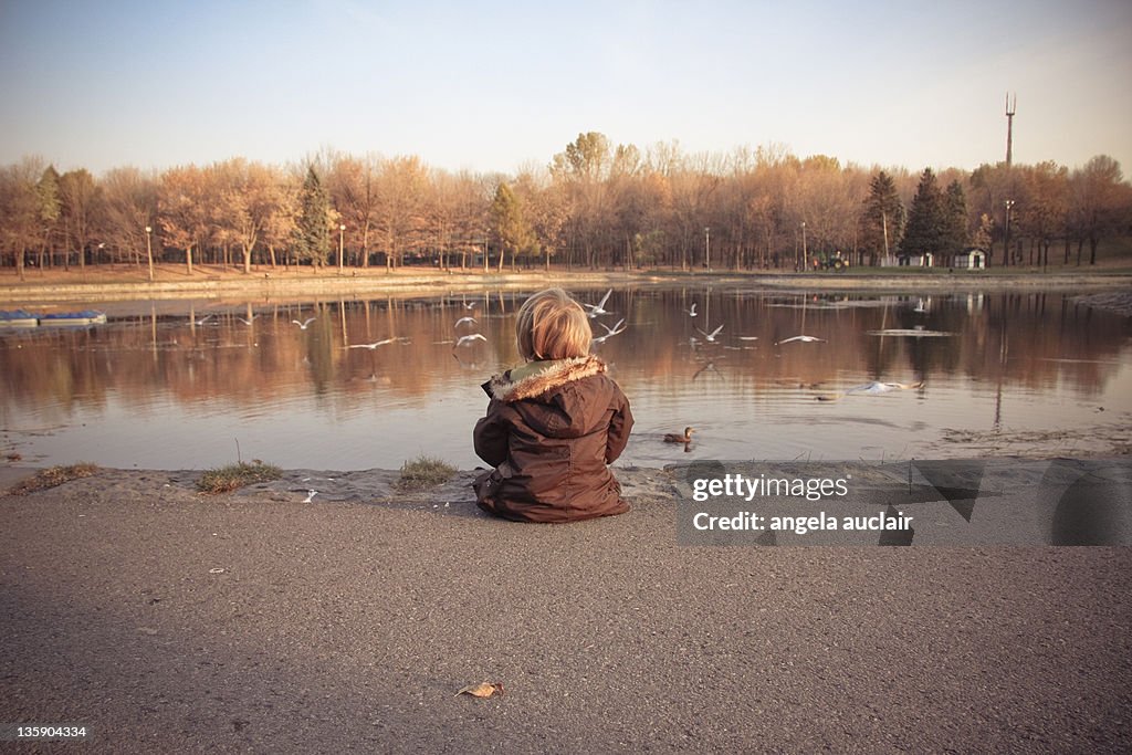 Boy sitting in near lake