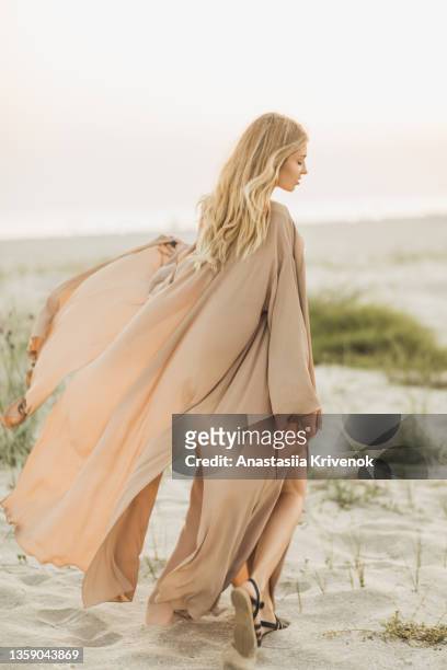 woman wearing beige silk developing dress against the seaside. - skinny blonde pics stock-fotos und bilder