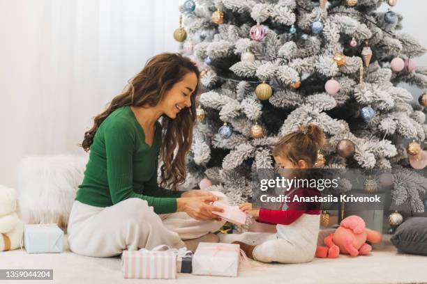 happy family with christmas gift near decorated christmas tre. - pracht tanne stock-fotos und bilder