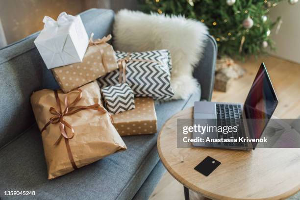 blue sofa with gifts and table with laptop and credit card for online christmas shopping. - red card fotografías e imágenes de stock