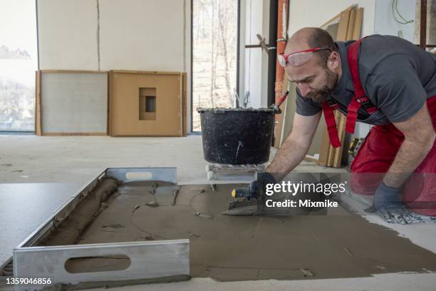 blue collar worker spreading adhesive on the floor - flooring contractor stock pictures, royalty-free photos & images