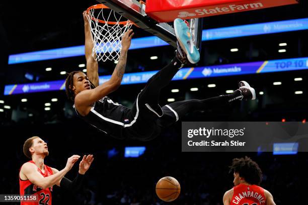 Nic Claxton of the Brooklyn Nets dunks the ball as Malachi Flynn of the Toronto Raptors looks on during the first half at Barclays Center on December...